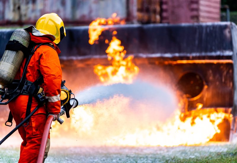 Firefighter using Chemical foam fire extinguisher to fighting with the fire flame from oil tanker truck accident. Firefighter safety disaster accident and public service concept.